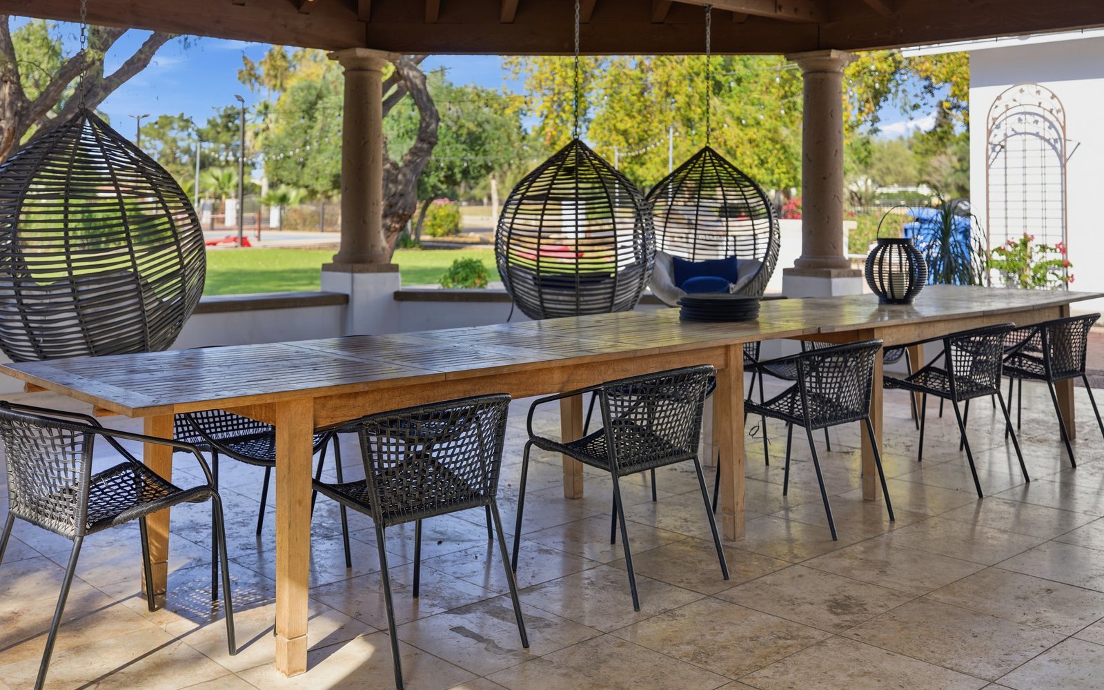 Covered patio with communal dining table and hanging chairs — Scottsdale